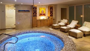 Un espace bien-être comprenant un jacuzzi, des fauteuils en osier et un meuble en bois agrémenté d’un objet décoratif.