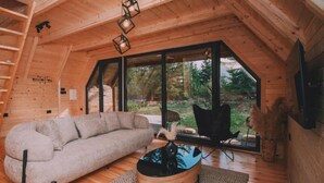 Une chambre mansardée chaleureuse, dotée d’une grande fenêtre, d’un canapé, d’une table basse et d’un fauteuil.