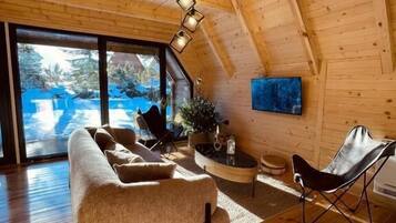 A cozy wooden interior with a sofa, a chair, and a TV on the wall.
