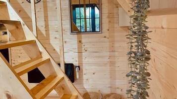 A wooden interior with a staircase, a window with bars, and a plant.