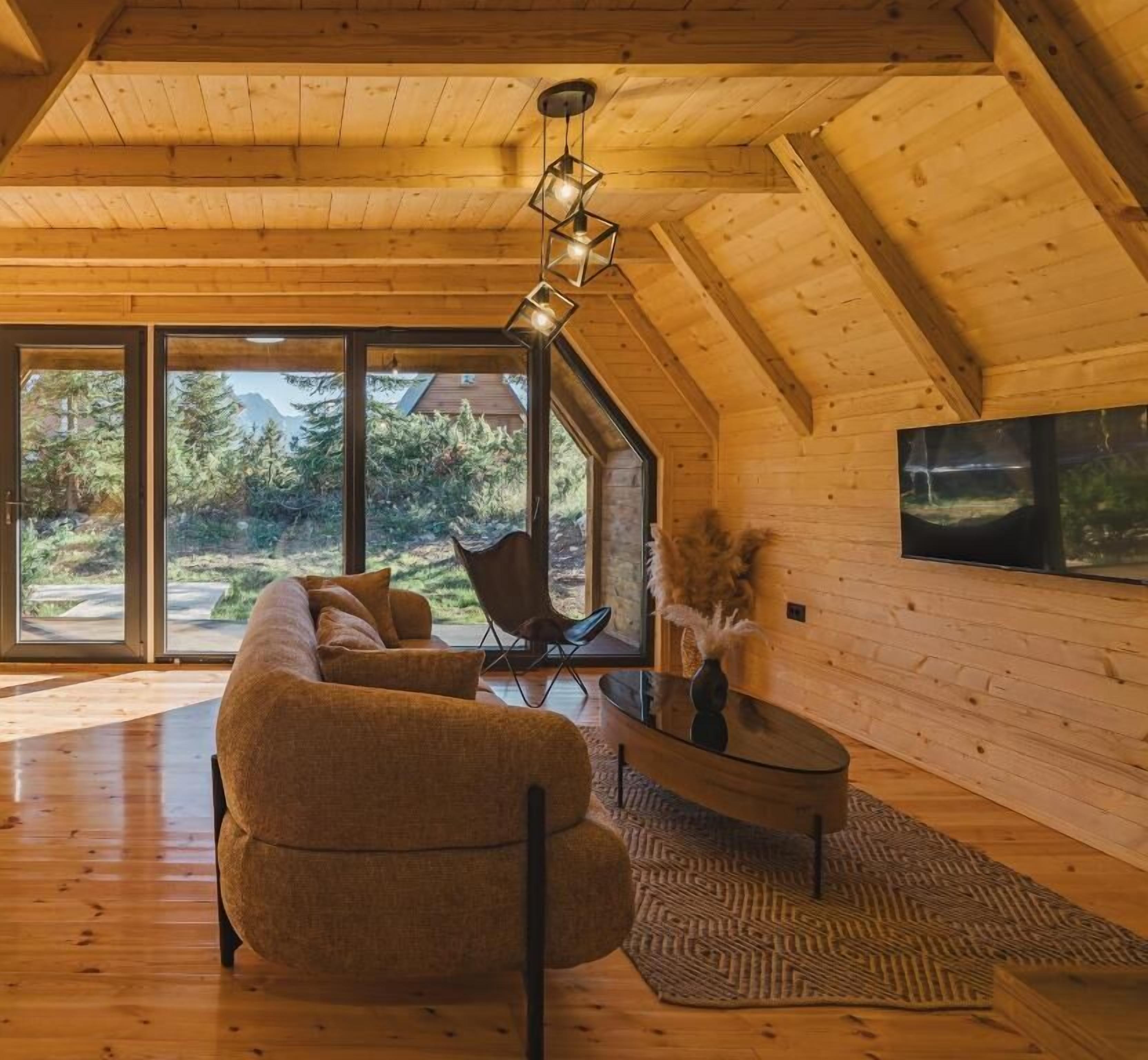 Un accogliente loft con una grande finestra, soffitto in legno e un divano moderno.