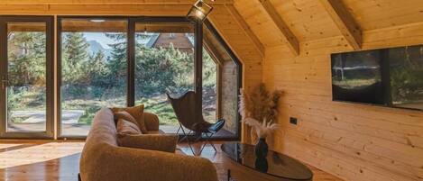 Un accogliente loft con una grande finestra, soffitto in legno e un divano moderno.