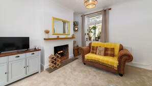 A living room with a television, fireplace, sofa, and a ceiling light fixture.