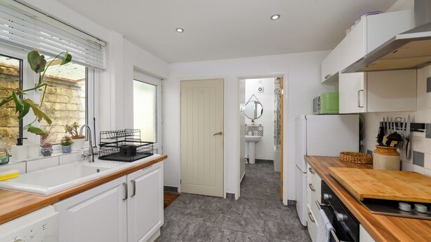 A modern kitchen with white cabinets, a wooden countertop, and a sink.
