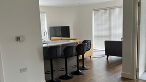 Eine moderne Küche mit einer zentralen Kochinsel, Barhocker und einem Essbereich mit einer Couch und Stühlen.