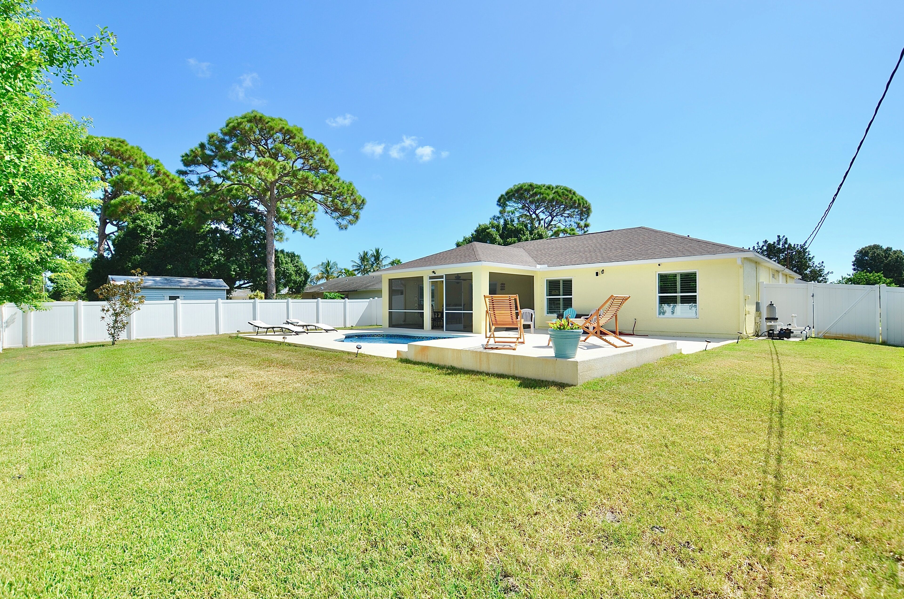 A single-story house with a covered patio, a swimming pool, and a fenced backyard.