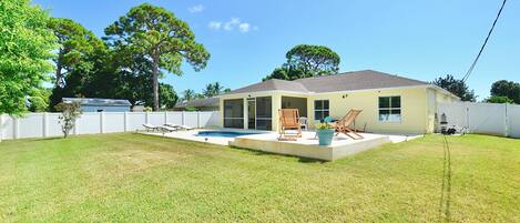 A single-story house with a covered patio, a swimming pool, and a fenced backyard.