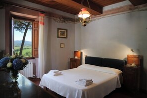 A bedroom with a bed, bedside tables, a lamp, a window with curtains, and a view of the outdoors. - Villa Cesari Tiberi - private pool and frescoes (Marsciano)