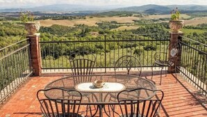 A terrace with a table and chairs, offering a view of a countryside landscape.