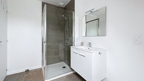 A modern bathroom with a glass-enclosed shower, a white vanity with a mirror, and a tiled floor. - House Roscoff 5 mn walk from the port (Roscoff)