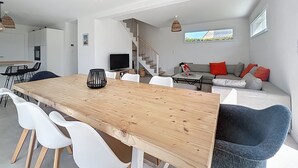 A modern living space with a dining area, kitchen, and a staircase leading to an upper level. - House Roscoff 5 mn walk from the port (Roscoff)