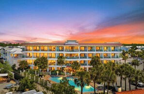 Un hôtel à plusieurs étages doté de balcons, d’une piscine et offrant une vue sur un ciel au coucher du soleil.