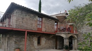 A stone building with a balcony, a potted plant, and a clear sky.