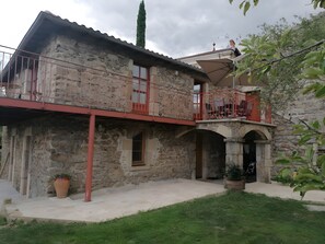 A stone building with a balcony, a potted plant, and a clear sky.