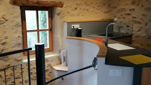 A kitchen with a stone wall, a window, a sink, and a countertop.