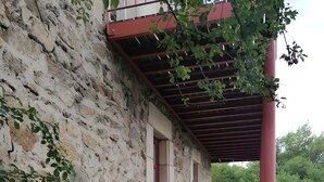 A stone building with a red door, a covered porch, and steps leading to the entrance.