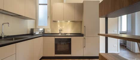 A modern kitchen with a built-in oven, a sink, and a window above the countertop.