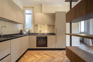 A modern kitchen with a built-in oven, a sink, and a window above the countertop.