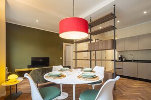 A modern dining area with a round table, white chairs, and a red pendant light.