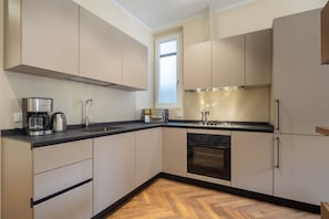 A modern kitchen with a black countertop, stainless steel appliances, and light-colored cabinets.