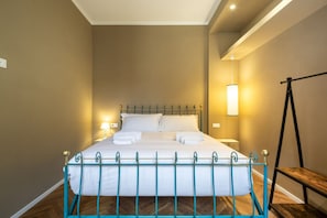 A neatly made bed with a metal frame, a bedside lamp, and a wooden bench. - Luxury Bridge Apartment (Florence)