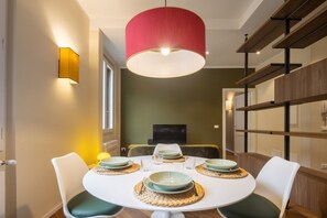 A dining area with a round table, white chairs, and a red pendant light.