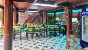 An outdoor seating area with wooden tables and chairs, a staircase, and a Pepsi refrigerator. - An Peaceful Homestay (Hai Phong)