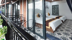 A hotel room with a balcony, large windows, and a bed with a white bedspread. - An Peaceful Homestay (Hai Phong)