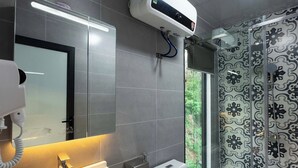 A modern bathroom with a large mirror, white sink, and toilet. There is a window with a view of greenery outside. - An Peaceful Homestay (Hai Phong)