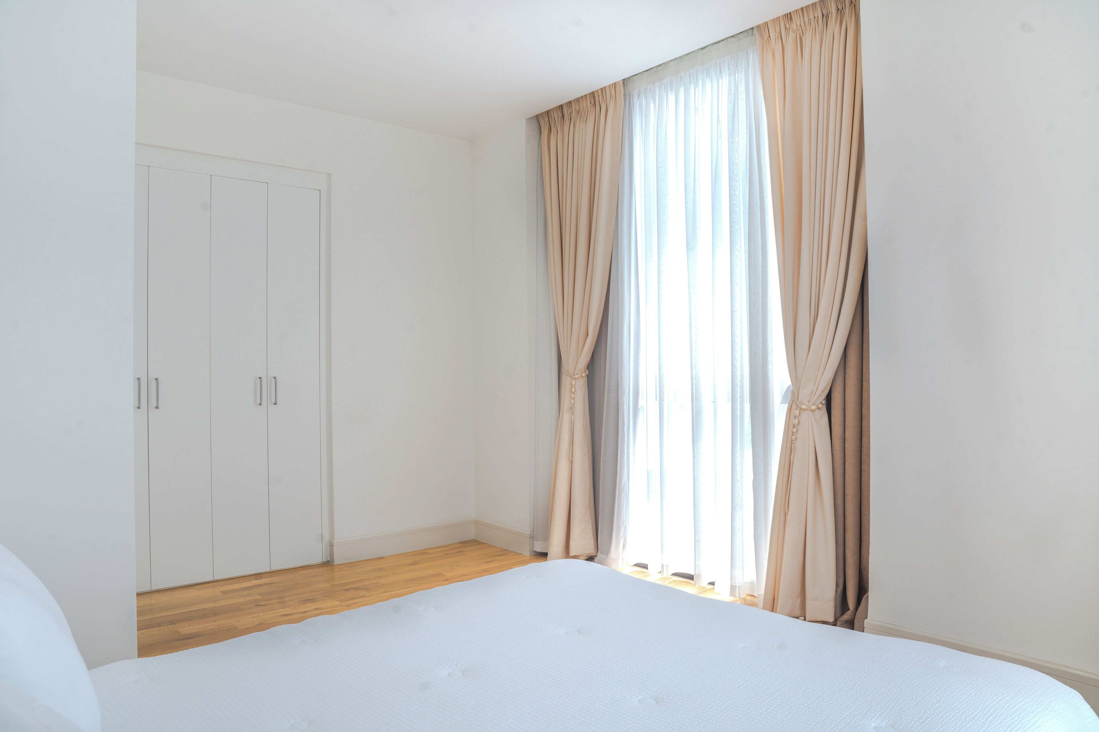A bedroom with a large bed, a wardrobe, and a window with curtains.