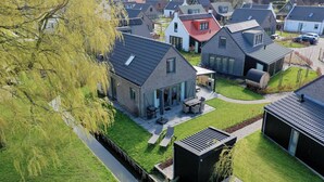 Una zona residencial con casas modernas, un césped bien cuidado y un estrecho canal de agua.