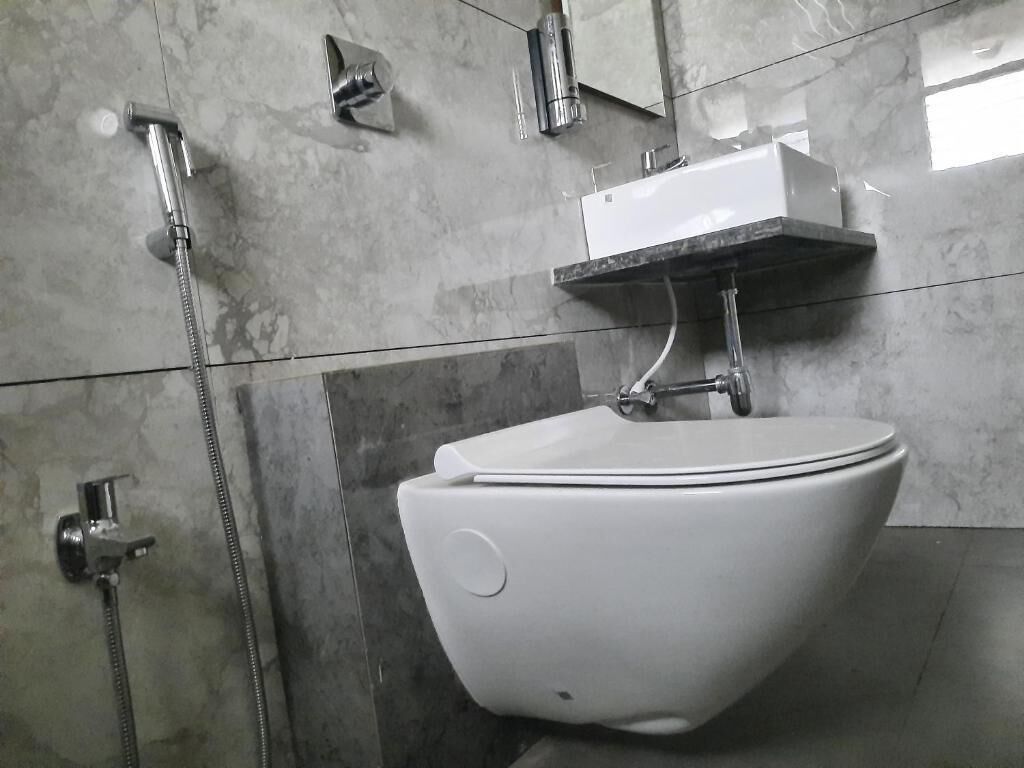 A bathroom with a white toilet, a shower, and a sink with a mirror above it.