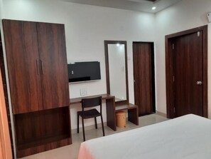 A bedroom with a bed, a desk, a chair, a wardrobe, and a television. - Raapan Beach Resort (Malvan)