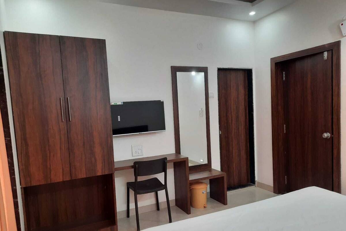 A bedroom with a bed, a desk, a chair, a wardrobe, and a television.
