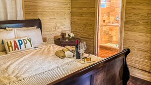 A wooden room with a bed, a nightstand, a bottle of wine, and a glass. - Cabaña Del Sol-Small Cabin Near The Best Beaches in Cabo Rojo with generator (Cabo Rojo)