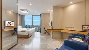 A modern hotel room with a bed, a desk, a chair, a television, and a large window offering a city view.
