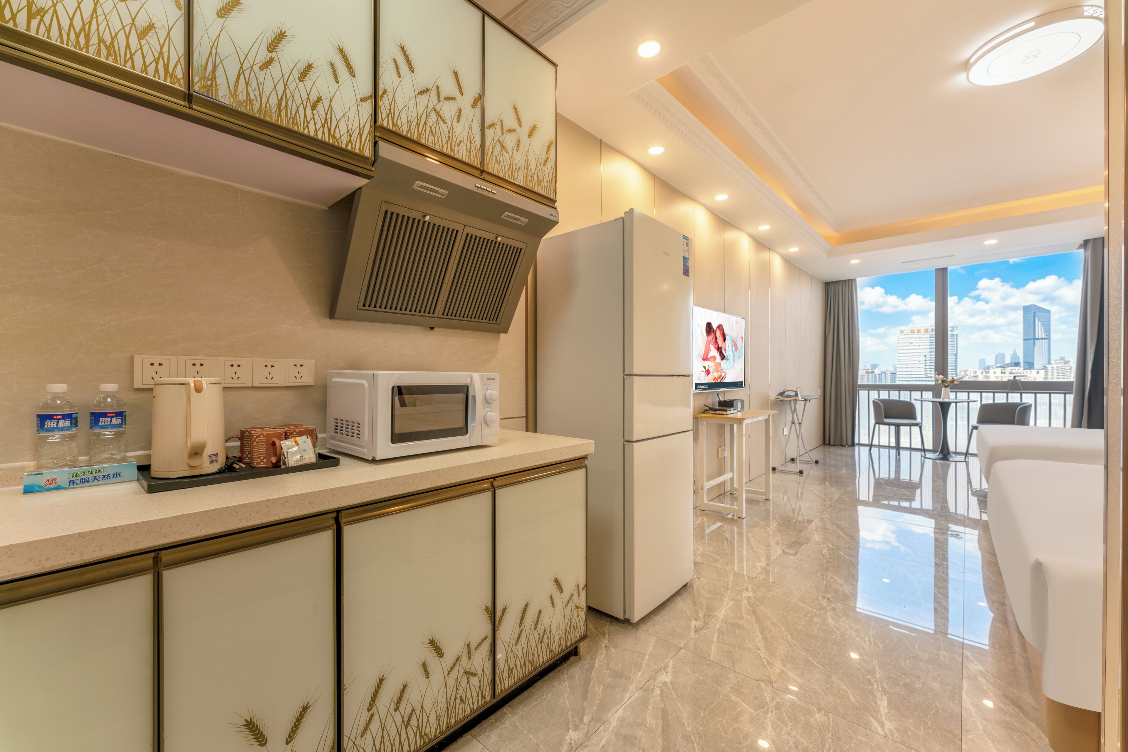 Una cocina moderna con microondas, refrigerador y cafetera. Hay un balcón con vistas a la ciudad.