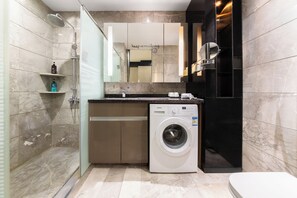 Une salle de bain moderne équipée d’une douche, d’un lave-linge encastré, de toilettes et d’un meuble-lavabo avec un miroir.