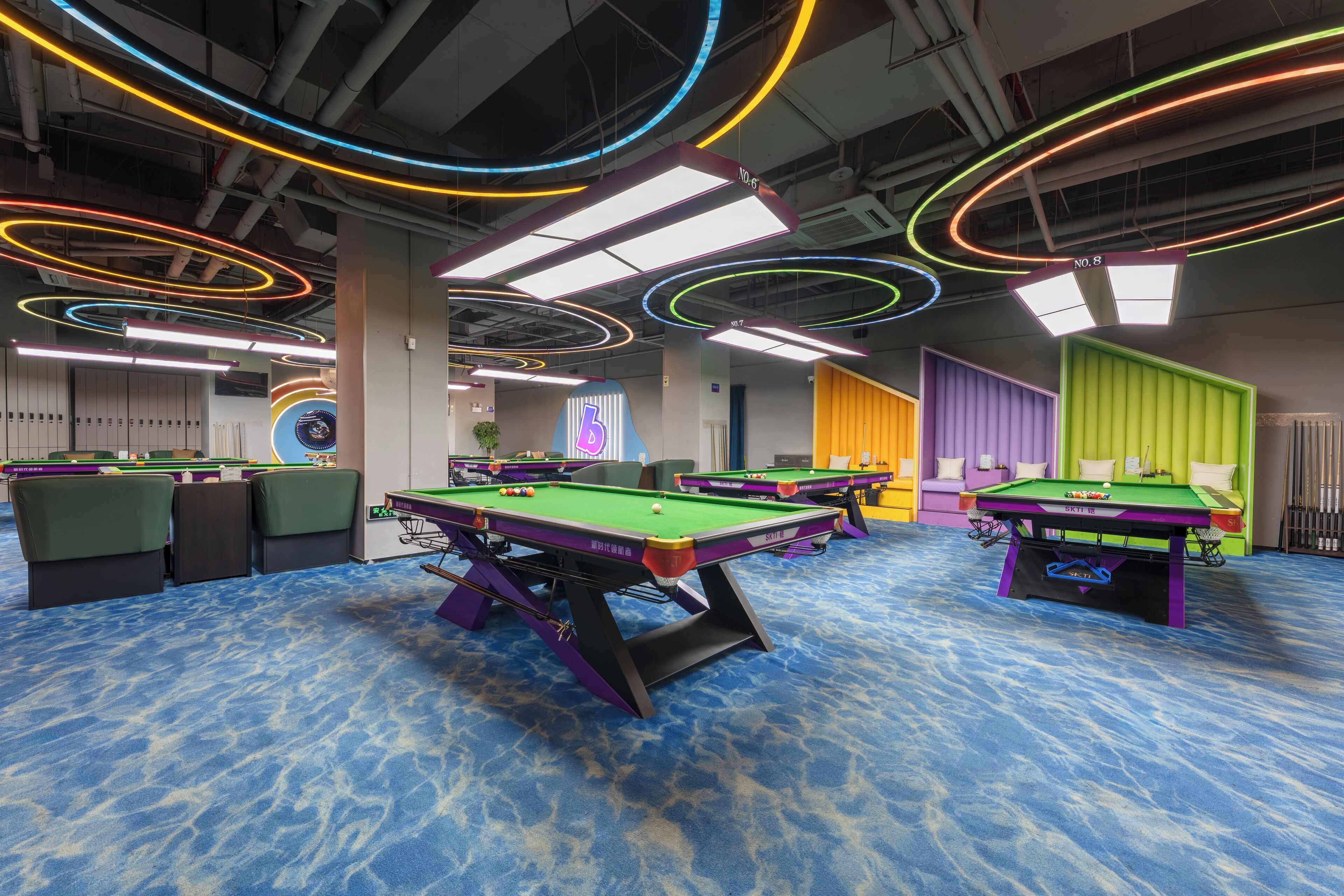 A pool hall with multiple pool tables, colorful neon lights, and a blue carpeted floor.
