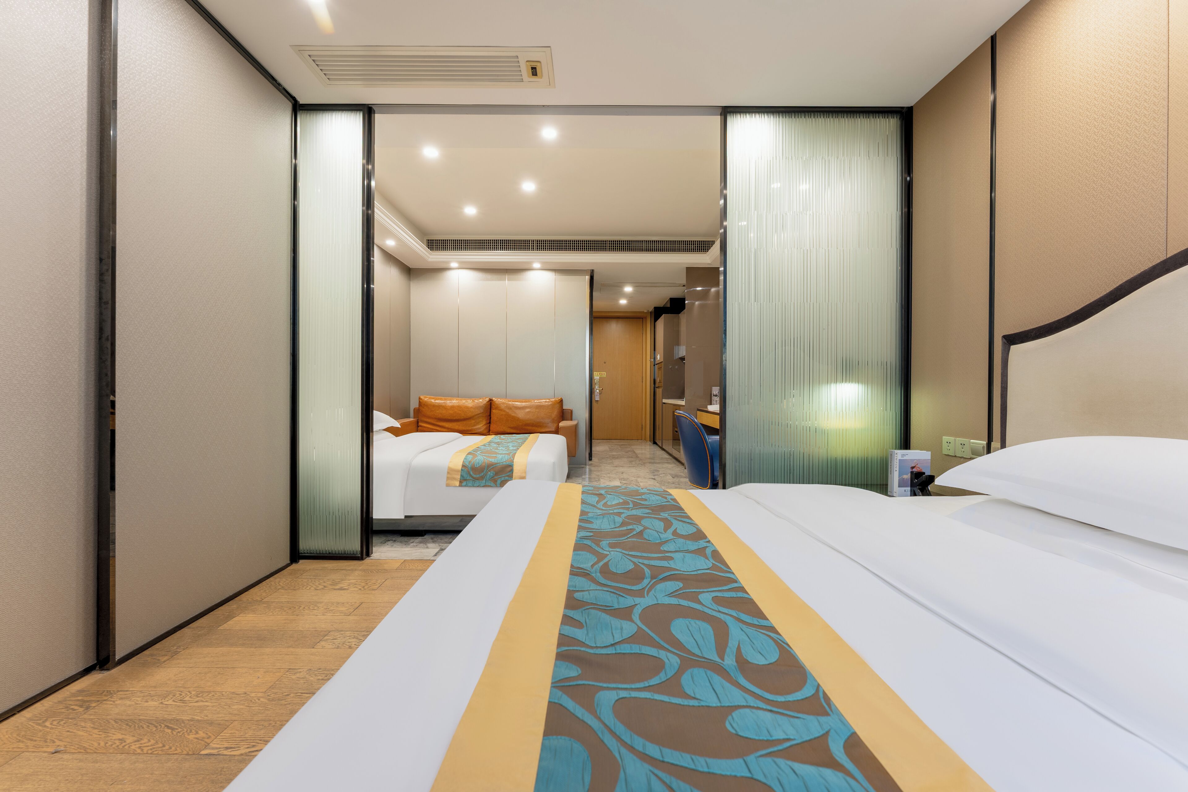 Une chambre d’hôtel avec un grand lit, un bureau et une chaise. On aperçoit une salle de bain à l’arrière-plan.