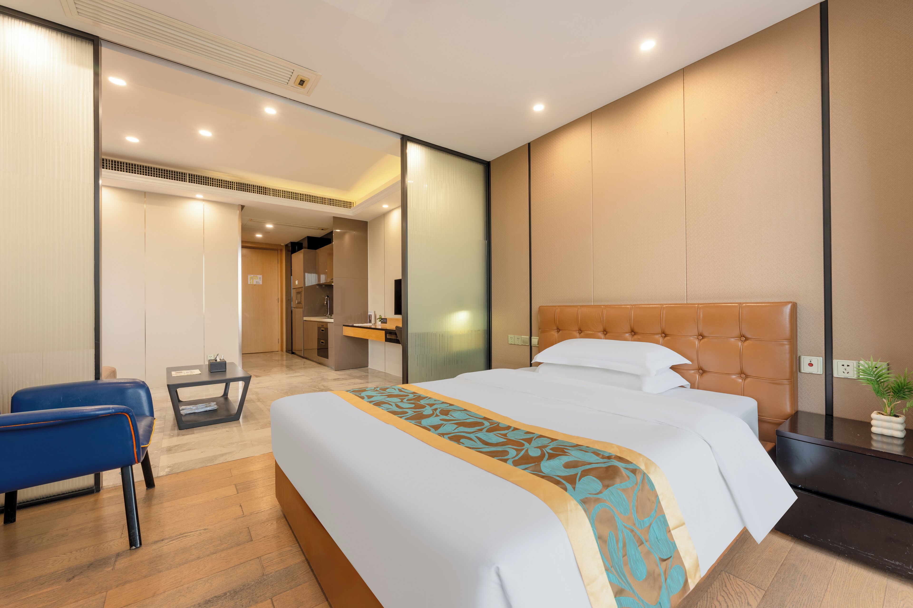 Una moderna camera d'albergo con un letto grande, una scrivania e una sedia. Si intravede un bagno sullo sfondo.