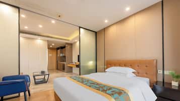 Una moderna camera d'albergo con un letto grande, una scrivania e una sedia. Si intravede un bagno sullo sfondo.