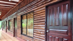 A corridor with wooden log walls, large windows, and a tiled floor. - Hotel Sun Sun Lodge (Horquetas)