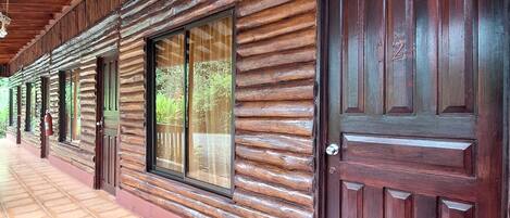 A corridor with wooden log walls, large windows, and a tiled floor.