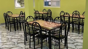 A dining area with multiple tables and chairs, a patterned floor, and a green wall. - Scarlett Near Mount Zion (Bugallon)