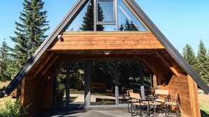 A modern, triangular wooden cabin with large windows and a covered patio area. - Mountain Home Durmitor 1 (Uskoci)