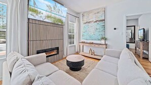 A modern living room with a fireplace, a large painting, and a view of the outdoors.