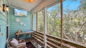 A covered porch with wicker furniture, a table, and decorative plates.