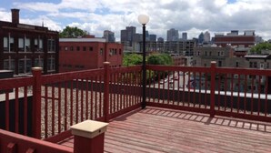 A red wooden deck with a city skyline in the background.