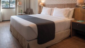 Ein Hotelzimmer mit einem großen Bett, Nachttischen und Blick auf die Stadt.